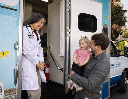 Two adults and a child stand by van.